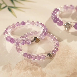 Detailed macro of amethyst beads with engraved clover silver charms on a stand