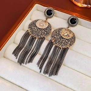 Close-up of vintage gold portrait earrings featuring black gemstones and tassels