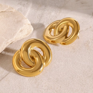 Close-up of 18k gold interlocking double circle earrings on a textured stone surface