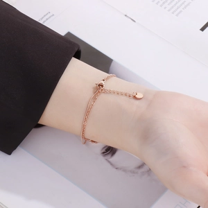 Close-up of double-layered rose gold sunflower bracelet with heart clasp on wrist