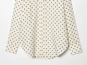 Detailed view of polka dot shirt with white buttons, curved hem and buttoned cuffs