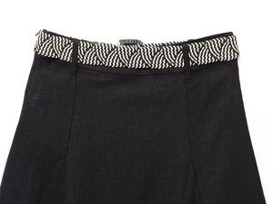 Detailed close-up of a black linen dress waist featuring a woven black and white belt