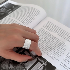Modern 925 sterling silver wide ring with irregular textured finish on a model's hand