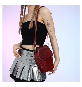 Detail of red patent leather shoulder bag with spider web pattern and glossy finish