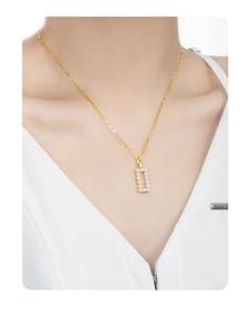 Detail of S925 silver necklace with golden D-shaped pendant inlaid with pearls