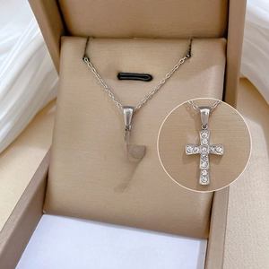 Macro shot of silver titanium steel cross pendant necklace with black enamel and zircon inlay