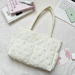 Detailed close-up of quilted floral tote bag with laptop and lifestyle accessories
