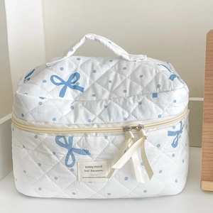 Close-up of white quilted cotton cosmetic bag with blue polka dots and a bow handle