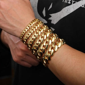 Golden Cuban link bracelet with butterfly clasp shown stacked on a model wrist