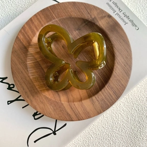 Macro shot of a translucent amber butterfly hair claw clip on a rustic wooden tray