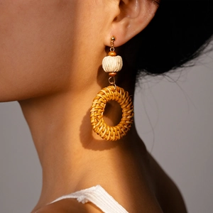 Close-up of bohemian style rattan drop earrings on a model with artistic lighting shadows
