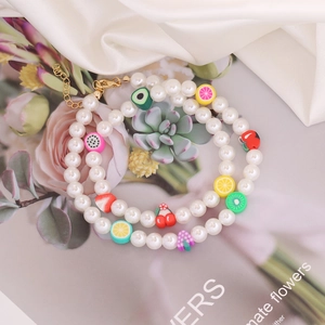 Bohemian pearl necklace featuring colorful clay fruit charms and golden extension chain