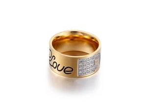 Close-up of golden wide ring with black Love script and sparkling zircon stone accents