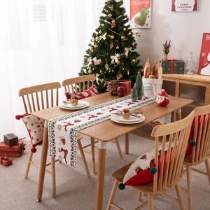 Modern Christmas table runner with elk and snowflake prints on a wooden festive table