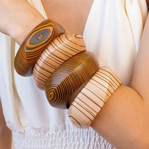 Stack of four minimalist wooden bangles with natural grain and rivet details on model