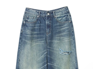 Macro detail of high waist blue washed jeans with whiskered texture and ripped accents