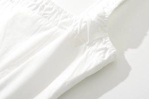 Dettaglio del tessuto bianco con design elastico a punto smock e ampie spalline chic