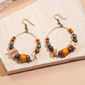 Ethnic bohemian hoop earrings with colorful wooden beads and shells on a stone background