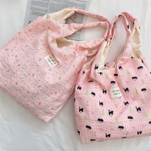 Detail of pink pleated tote bags featuring cute rabbit and black cat printed patterns