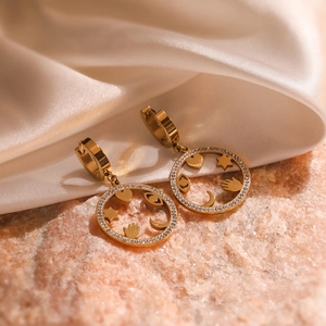 Boucles d'oreilles circulaires dorées géométriques avec zircon sur fond de soie blanche