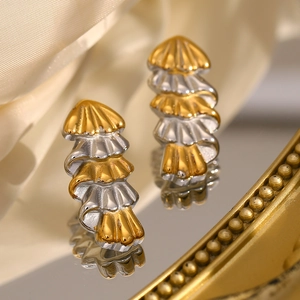 Macro view of tiered gold and silver Christmas tree earrings on satin fabric