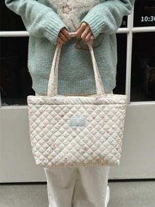 Close-up of quilted cotton tote bag with small pink floral patterns and brand label