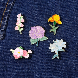 Set of 5 floral enamel pins featuring lilies and violets on dark denim background