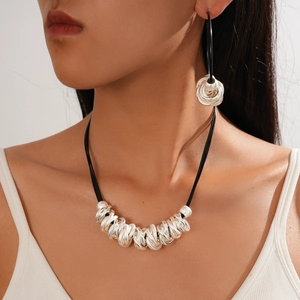 Detail of silver geometric knotted necklace and earrings on model with black leather cord