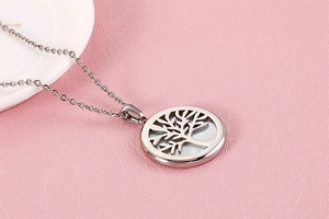 Macro detail of silver tree of life pendant with white inlay on pink background
