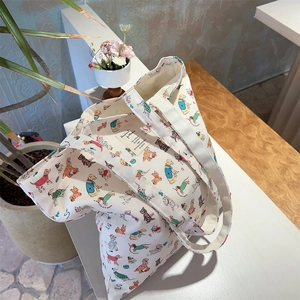 Detailed view of canvas tote bag with cute dog illustrations and fabric label texture