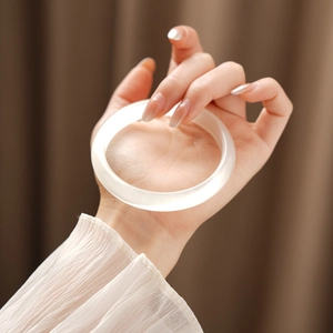 Detail of a translucent cat-eye stone bracelet with a high gloss finish on a model's hand