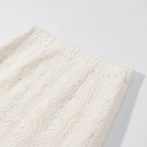 Close-up of intricate floral lace embroidery on cream white fabric with detailed textures
