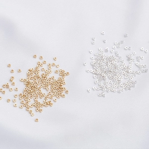 Macro detail of 14K gold and silver plated 2mm triangle spacer beads for DIY jewelry making