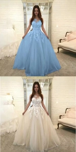 Close-up of intricate lace bodice and multi-layered tulle skirt on evening gowns