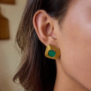 Vintage gold rectangular earrings with green gemstone inlay on model's ear