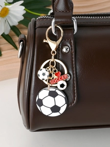 Soccer keychain with ball pendants and red soccer tag hanging on a brown leather bag