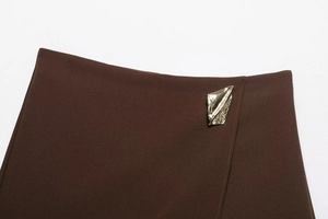 Detail of dark brown skirt waist featuring a unique gold metal buckle and textured fabric
