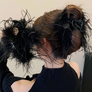 Détail d'une pince à cheveux luxueuse en plumes noires avec ornement logo léopard doré