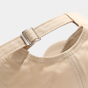 Macro view of adjustable metal buckle and stitching on beige cotton baseball cap