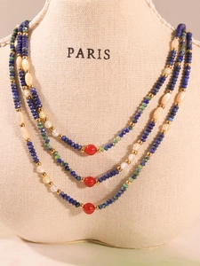 Detailed view of lapis beads and red agate pendant on a jewelry display bust
