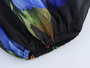 Detailed close-up of floral chiffon fabric texture and elastic hem on a short-sleeved top