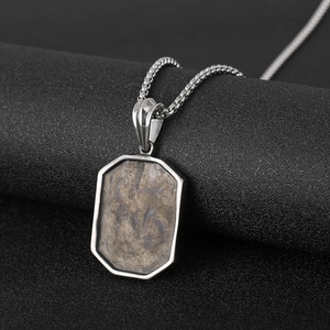 Close-up of vintage titanium steel necklace with a rectangular metal pendant on a stand