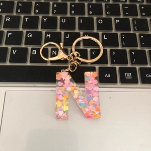 Macro view of a resin letter N keychain with colorful heart sequins on a keyboard