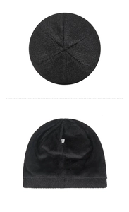 Detailed view of a black knitted beanie hat showing plush lining and top seam texture.