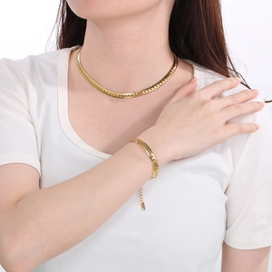 Close-up of gold Cuban link chain set worn on a model with white T-shirt backdrop