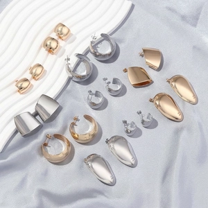 Minimalist irregular geometric gold and silver stud earrings on a silk background