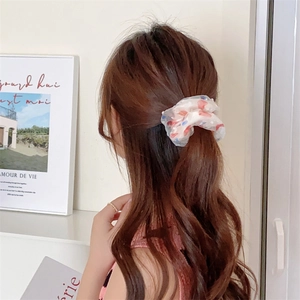 Detail of a white polka dot mesh hair scrunchie worn on hair in a cozy home setting