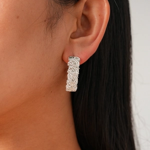 Detailed view of silver hoop earring featuring a unique twisted nest texture on model