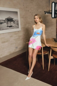 Detailed view of white floral dress with blue and pink flowers in a lifestyle setting