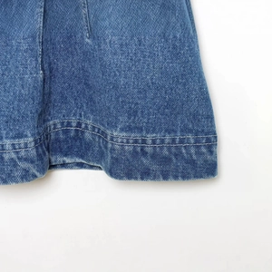 Detailaufnahme des blauen Denim-Oberteils mit Doppelnaht-Saum und Stoffstruktur